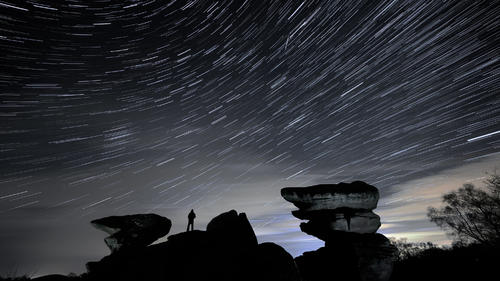 15.12.2020, Großbritannien, Harrogate: Ein Mann beobachtet den Himmel über der Felsformation Brimham Rocks während des Geminiden-Meteoritenschauers. (Foto mit Mehrfachbelichtung nachbearbeitet) Foto: Danny Lawson/PA Wire/dpa +++ dpa-Bildfunk +++