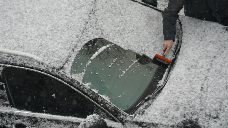 15.02.2021, Hamburg: Ein Mann befreit die Windschutzscheibe seines Fahrzeugs vom Neuschnee. Foto: Marcus Brandt/dpa +++ dpa-Bildfunk +++