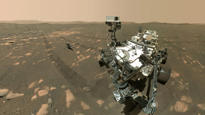 This Tuesday, April 6, 2021 image made available by NASA shows the Perseverance Mars rover, foreground, and the Ingenuity helicopter about 13 feet (3.9 meters) behind. This composite image was made by the WASTON camera on the rover's robotic arm on t