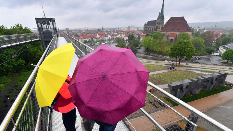 12.05.2021, Thüringen, Erfurt: Besucherinnen der Bundesgartenschau (BUGA) stehen bei Regenwetter auf dem Petersberg mit Blick auf die Stadt mit Mariendom und Severikirche. Vom 23. April bis 10. Oktober 2021 findet das Sommerfest mit gärtnerischer Lei