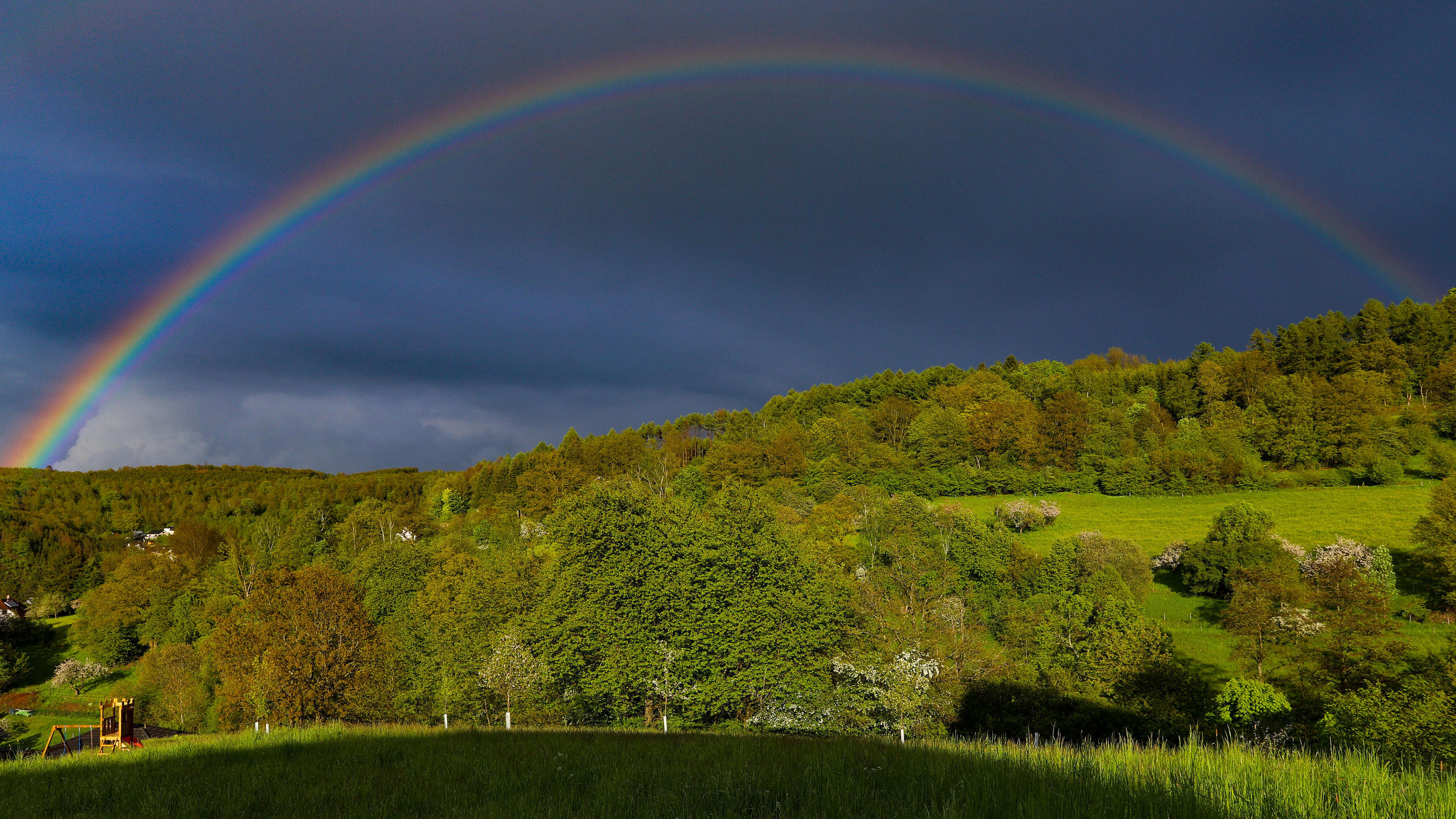 Frühling im Siegerland, nach erneutem Regen am Abend zeigt sich ein Regenbogen über dem Ort Siegen-Oberschelden.