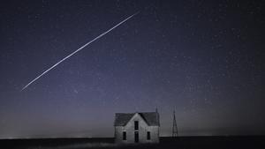 In this photo made with a long exposure, a string of SpaceX StarLink satellites passes over an old stone house near Florence, Kan., on Thursday, May 6, 2021. (AP Photo/Reed Hoffmann, File)