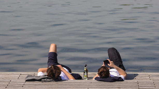 01.06.2021, Schleswig-Holstein, Lübeck: Junge Männer genießen das sonnige Wetter auf dem Drehbrückenplatz. Das sommerliche Wetter soll auch in den kommenden Tagen anhalten. Foto: Ulrich Perrey/dpa +++ dpa-Bildfunk +++