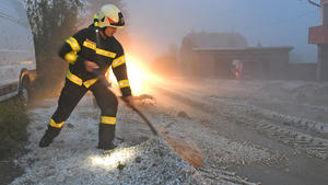 22.06.2021, Österreich, Pinsdorf: Feuerwehrleute räumt Hagel zur Seite. In Österreich haben Unwetter mit großen Hagelkörnern zahlreiche Gebäude und Autos beschädigt. Foto: Wolfgang Spitzbart/APA/dpa +++ dpa-Bildfunk +++