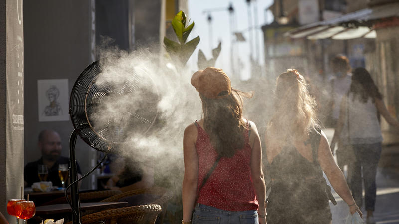 29.06.2021, Spanien, Madrid: Eine Frau kühlt sich vor der Hitze mit einem Wasserdampfdiffusor vor einem Restaurant in der Alcala Straße. Es werden Höchsttemperaturen von bis zu 36 Grad Celsius erwartet. Foto: Jesús Hellín/EUROPA PRESS/dpa +++ dpa-Bil
