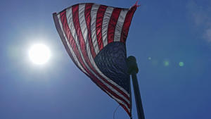 ARCHIV - 30.06.2021, USA, Seattle: ILLUSTRATION - Eine US-Flagge weht  mit der Sonne im Hintergrund in der Innenstadt. (zu dpa: «Forscher: Hitzewelle in Nordamerika ohne Klimawandel quasi undenkbar») Foto: Ted S. Warren/AP/dpa +++ dpa-Bildfunk +++