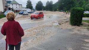 18.07.2021, Bayern, Bischofswiesen: Eine Frau beobachtet wie ein Auto durch die überspülte Straße fährt. Der Landkreis Berchtesgadener Land hat nach starkem Regen wegen Hochwassers den Katastrophenfall ausgerufen. Foto: Kilian Pfeiffer/dpa +++ dpa-Bildfunk +++