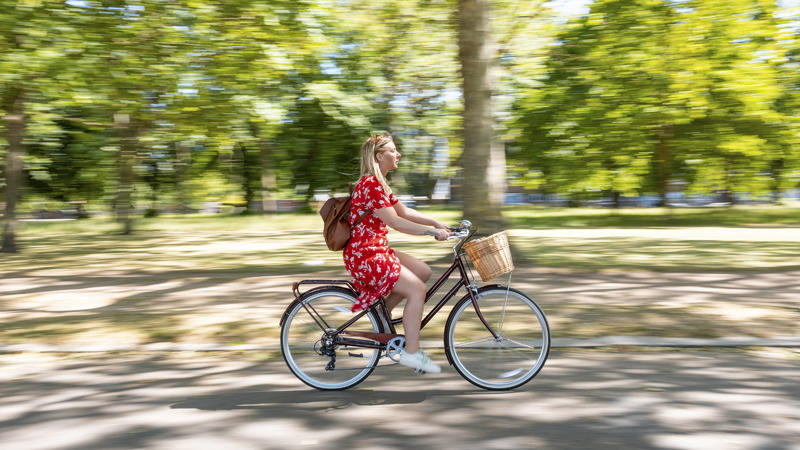 Blurred motion of woman riding bicycle on footpath at public park model released Symbolfoto PUBLICATIONxINxGERxSUIxAUTxHUNxONLY WPEF03064
