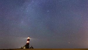 06.08.2021, Großbritannien, Happisburgh: Eine Sternschnuppe ist am Sternenhimmel über dem Leuchtturm von Happisburgh zu sehen. Durch einen Meteoritenstrom, die sogenannten Perseiden, die jährlich in der ersten Augusthälfte wiederkehren, kann man besonders in den Nächten zum 12. und 13. August eine Vielzahl an Sternschnuppen am Nachthimmel sehen. Foto: Joe Giddens/PA Wire/dpa +++ dpa-Bildfunk +++