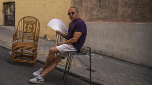 15.08.2021, Spanien, Madrid: Ein Mann sitzt am Rande des Flohmarktes El Rastro auf der Straße und fächert sich bei heißem Wetter etwas Wind zu. Spanien verzeichnete mit mehr als 47 Grad Celsius einen Hitzerekord. Foto: Andrea Comas/AP/dpa +++ dpa-Bildfunk +++