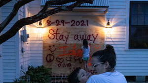 Christina Bourg snuggles her son Jean-Luc, 8, as her daughter Olivia, 10, places the finishing touches on a sign they painted after boarding up their property in preparation for Hurricane Ida in Morgan City, Louisiana, U.S., August 28, 2021.  REUTERS/Adrees Latif     TPX IMAGES OF THE DAY