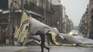 29.08.2021, USA, New Orleans: Ein Mann geht an einem Teil des Daches vorbei, das durch den Hurrikan Ida von einem Gebäude im French Quaeter weggeblasen wurde. Foto: Eric Gay/AP/dpa +++ dpa-Bildfunk +++