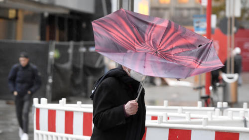 21.10.2021, Nordrhein-Westfalen, Köln: Der Regenschirm eines Passanten wird vom Sturm erfasst. Der Wetterdienst hat für heute im südlichen Nordrhein-Westfalen eine Unwetterwarnung mit orkanähnlichen Böen und Starkregen vorhergesagt. Foto: Roberto Pfeil/dpa +++ dpa-Bildfunk +++