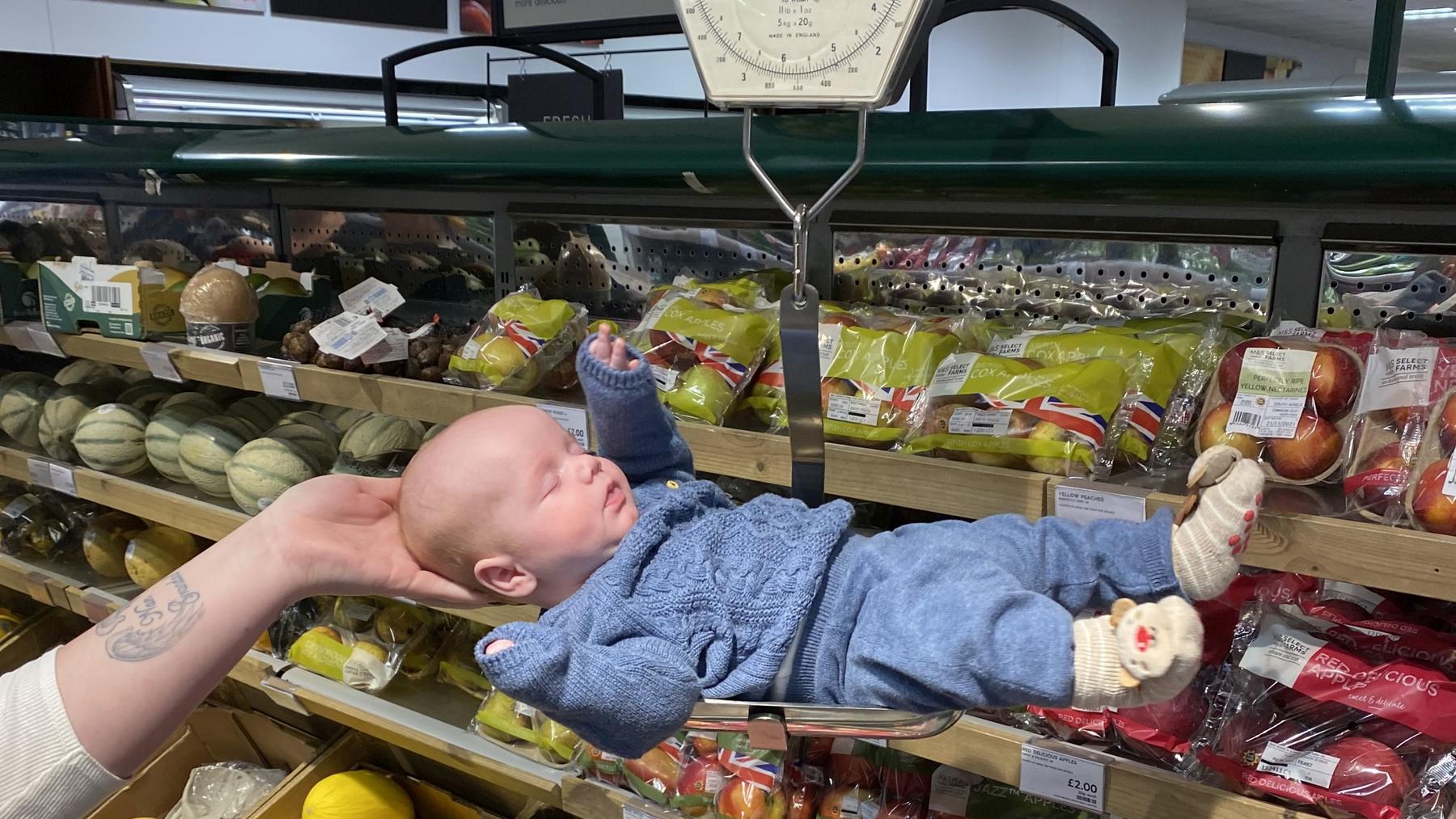 Baby liegt auf einer Waage im Supermarkt