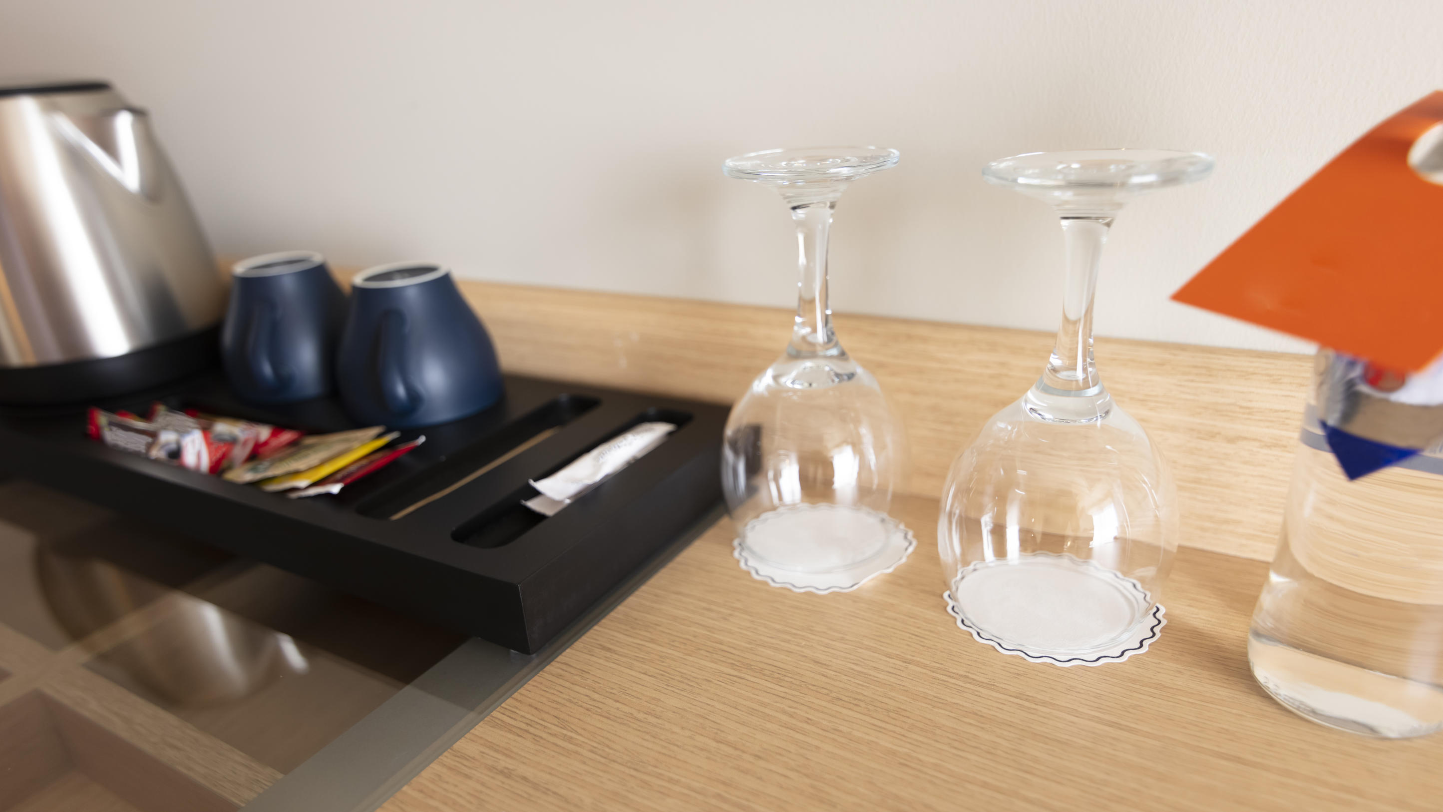 In einem Hotelzimmer steht eine Kaffeemaschine mitsamt Tassen und Gläsern bereit, damit Gäste sich nach ihrer Ankunft wohlfühlen können.