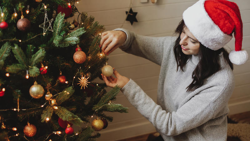 Frau schmückt ihren Miet-Weihnachtsbaum.