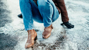 Unrecognizable woman has fallen down on an icy street in winter.