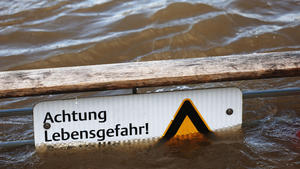 05.01.2022, Nordrhein-Westfalen, Köln: Ein Warnschild mit der Aufschrift "Achtung Lebensgefahr", das vor dem Schwimmen im Rhein warnt, ragt zum Teil aus dem Wasser. Der Wasserstand im Rhein bei Köln steigt momentan an. Der Pegel stand am Mittwoch bei 5,68 Metern, wie die Kölner Stadtentwässerungsbetriebe mitteilten. Foto: Oliver Berg/dpa +++ dpa-Bildfunk +++