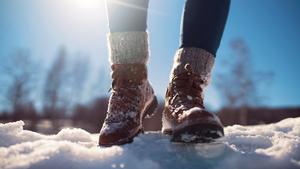 Close-up of a female mountaineer legs walking through snow.
