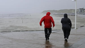Zwei Passanten in Regenkleidung gehen am 13.09.2017 auf Norderney (Niedersachsen) bei stürmischem Wetter die Strandpromenade entlang. (zu dpa "Herbsturm bringt Orkanböen und Sturmflut für die Nordseeküste" vom 13.09.2017) Foto: Volker Bartels/dpa +++(c) dpa - Bildfunk+++