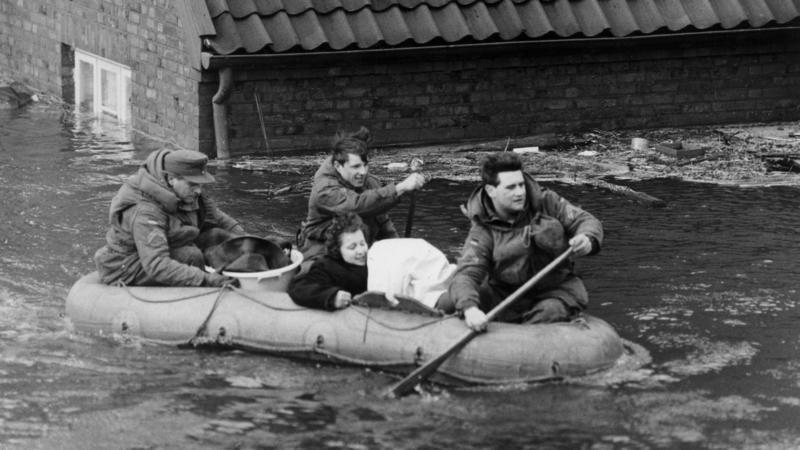 ARCHIV - 17.02.1962, Hamburg: Eine Frau wird mit einem Schlauchboot in Sicherheit gebracht. Im Hamburger Elbgebiet und im norddeutschen Küstenraum verursacht Sturmtief «Vincinette» in der Nacht zum 17. Februar 1962 die bis dahin schwerste Sturmflut d