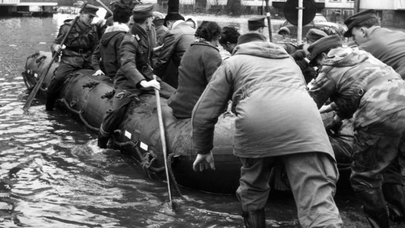 ARCHIV - 17.02.1962, Hamburg: Bundeswehrsoldaten bringen von der Sturmflut betroffene Menschen in einem Schlauchboot in Sicherheit. Im Hamburger Elbgebiet und im norddeutschen Küstenraum verursacht Sturmtief «Vincinette» in der Nacht zum 17. Februar 