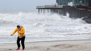 A person walks as waves break on the beach in the wake of Storm Eunice in Blankenberge, Belgium, February 18, 2022. REUTERS/Yves Herman