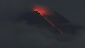 Lava flows down from the crater of Mount Merapi seen from Pakembinangun village in Sleman, Central Java, Thursday, March 10, 2022. Indonesia's Mount Merapi volcano spewed avalanches of hot clouds in eruptions overnight Thursday that forced about 250 residents to flee to temporary shelters. No casualties were reported. (AP Photo/Ranto Kresek)