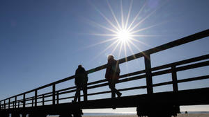 03.03.2022, Schleswig-Holstein, Föhr: Spaziergänger sind bei strahlendem Sonnenschein auf einer Seebrücke in Wyk auf der Nordseeinsel Föhr unterwegs. Foto: Christian Charisius/dpa +++ dpa-Bildfunk +++