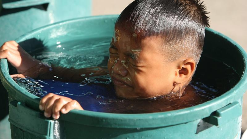 A Filipino boy takes a dip into a container of water, outside their shanty in an urban poor district of Quezon City, east of Manila, Philippines 21 March 2010. The United Nations marks World Water Day on 22 March with the theme, 'Clean Water for a He