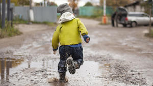 The child runs through the puddles. Naughty boy runs away from Mom. Carefree childhood in the city. Soiled clothes require washing. the boy is moving fast. || Modellfreigabe vorhanden