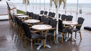 04.04.2022, Schleswig-Holstein, Lübeck-Travemünde: Zusammengestellte Tische und Stühle stehen im Regen an der Promenade der Ostsee. Foto: Daniel Bockwoldt/dpa +++ dpa-Bildfunk +++