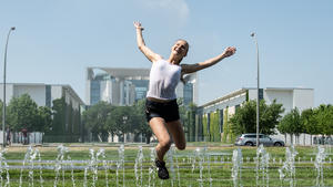 31.05.2018, Berlin: Johanna aus Frankfurt am Main springt über die Wasserfontänen vor dem Bundeskanzleramt. Foto: Paul Zinken/dpa | Verwendung weltweit