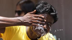 28.04.2022, Indien, Mumbai: Ein Mann spritzt sich an einem extrem heißen Tag auf einem Marktplatz Wasser ins Gesicht. Indien und Pakistan leiden unter einer frühen Hitzewelle. Indien hat bereits den heißesten März seit Beginn der Wetteraufzeichnungen vor 122 Jahren erlebt. Foto: Rajanish Kakade/AP/dpa +++ dpa-Bildfunk +++