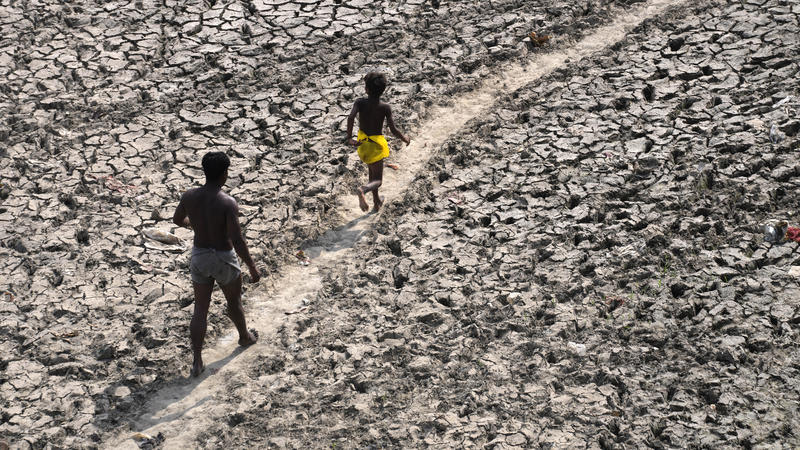A man and a boy walk across an almost dried up bed of river Yamuna following hot weather in New Delhi, India, Monday, May 2, 2022. An unusually early and brutal heat wave is scorching parts of India, where acute power shortages are affecting millions