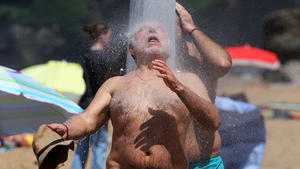 18.05.2022, Frankreich, Biarritz: Menschen kühlen sich unter einer Dusche am Strand von Biarritz im Südwesten von Frankreich ab. Es wird erwartet, dass das heiße Wetter mehrere Tage lang im ganzen Land anhält. Foto: Bob Edme/AP/dpa +++ dpa-Bildfunk +++
