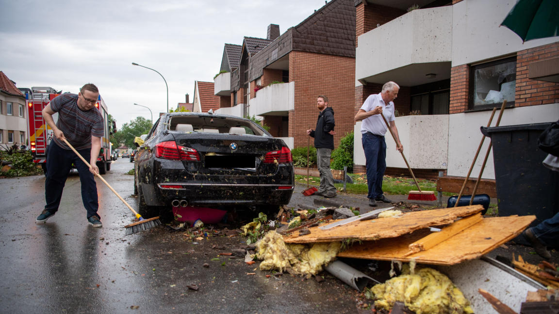 20.05.2022, Nordrhein-Westfalen, Paderborn: Leute fegen Trümmer von der Straße. Ein Unwetter hat auch in Paderborn große Schäden angerichtet. Foto: Lino Mirgeler/dpa +++ dpa-Bildfunk +++