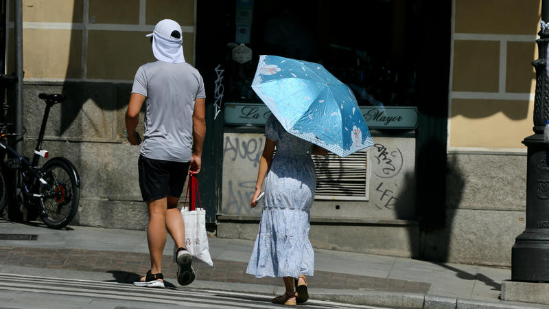 17.05.2022, Spanien, Madrid: Eine Frau schützt sich in Madrid mit einem Schirm vor der Sonne. In Spanien herrschen für diese Jahreszeit ungewöhnlich hohe Temperaturen, die in einigen Gebieten 40 Grad Celsius erreichen. Nach Angaben des Wetterdienstes
