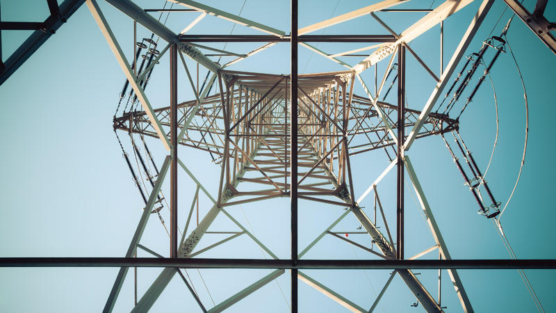 Picture of an electrical tower or pylon, blue sky in the background. Power grid or smart grid.