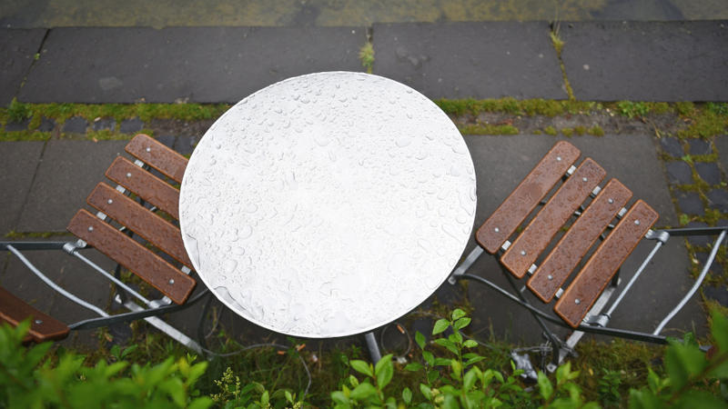 Vom Regen nasse Stühle und ein Tisch stehen am 19.06.2015 in einem Biergarten im Blücherpark in Köln (Nordrhein-Westfalen). Auch zum kalendarischen Sommmeranfang am 21.06.2015 soll das Wetter kühl und regnerisch bleiben. Foto: Henning Kaiser/dpa +++(