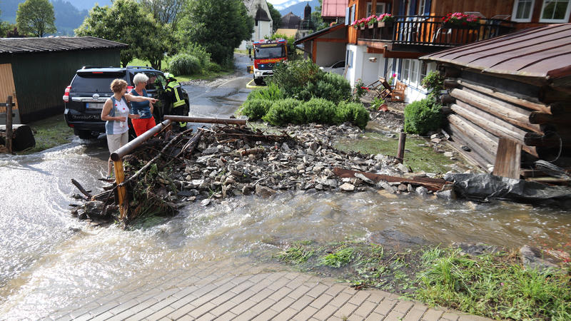 Anwohner betrachten die Schäden durch starke Regenfälle. Starkregen hat am Donnerstag zahlreiche Straßen im südlichen Allgäu überflutet.