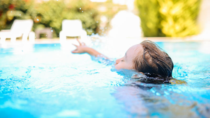 Ein Kind schwimmt im Freibad.