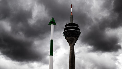 06.07.2022, Nordrhein-Westfalen, Düsseldorf: Dunkle Wolken ziehen hinter dem Fernsehturm am Rheinufer her. In Nordrhein-Westfalen müssen sich die Menschen zum Ende der Woche hin auf viele Wolken und vereinzelt Regen einstellen. Foto: Federico Gambarini/dpa +++ dpa-Bildfunk +++