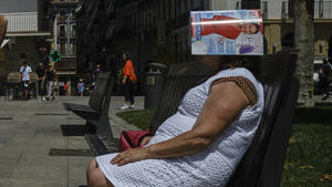 15.06.2022, Spanien, Pamplona: Eine Frau schützt ihren Kopf unter einer Zeitschrift auf dem Plaza del Castillo. Eine schon seit dem vergangenen Wochenende andauernde, ungewöhnlich früh im Jahr auftretende Hitzewelle in Spanien erfasste am Mittwoch auch Gebiete im Zentrum und Nordosten des Landes. Foto: Alvaro Barrientos/AP/dpa +++ dpa-Bildfunk +++