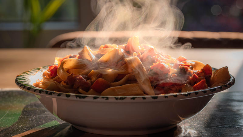 Einer Teller mit Nudeln, Pasta, steht dampfend auf einem Esstisch. Bei der Hitze am besten auf deftige schwere Speisen verzichten.