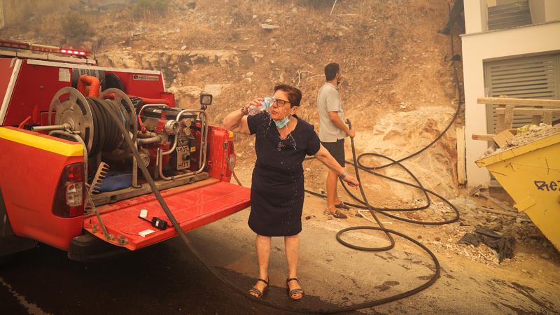 Eine Frau schüttet sich Wasser über ihr Gesicht. Anfang Juni wütete ein Lauffeuer am Stadtrand von Athen. Die Flammen verbrannten Autos, bedrohten Häuser und Stromleitungen.