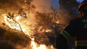 A firefighter watches a wildfire burn in Zaton, Croatia, Wednesday, July 13, 2022. Fueled by strong winds, fires raged at Croatia's Adriatic Sea, with the most dramatic situation reported near the town of Sibenik, where water-dropping planes and dozens of firefighters struggled to contain the flames that briefly engulfed some cars and the church tower in the Zaton area on the outskirts of the town before firefighters managed to put it out. (AP Photo)