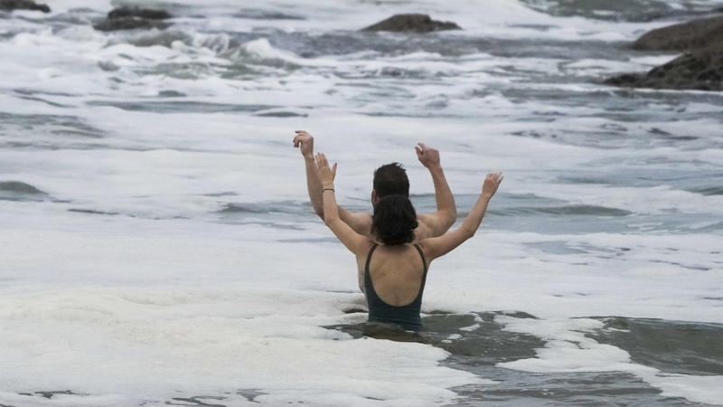 A couple react as they take a mid-winter swim at Bronte Beach as rain continues to fall in Sydney, Australia, 