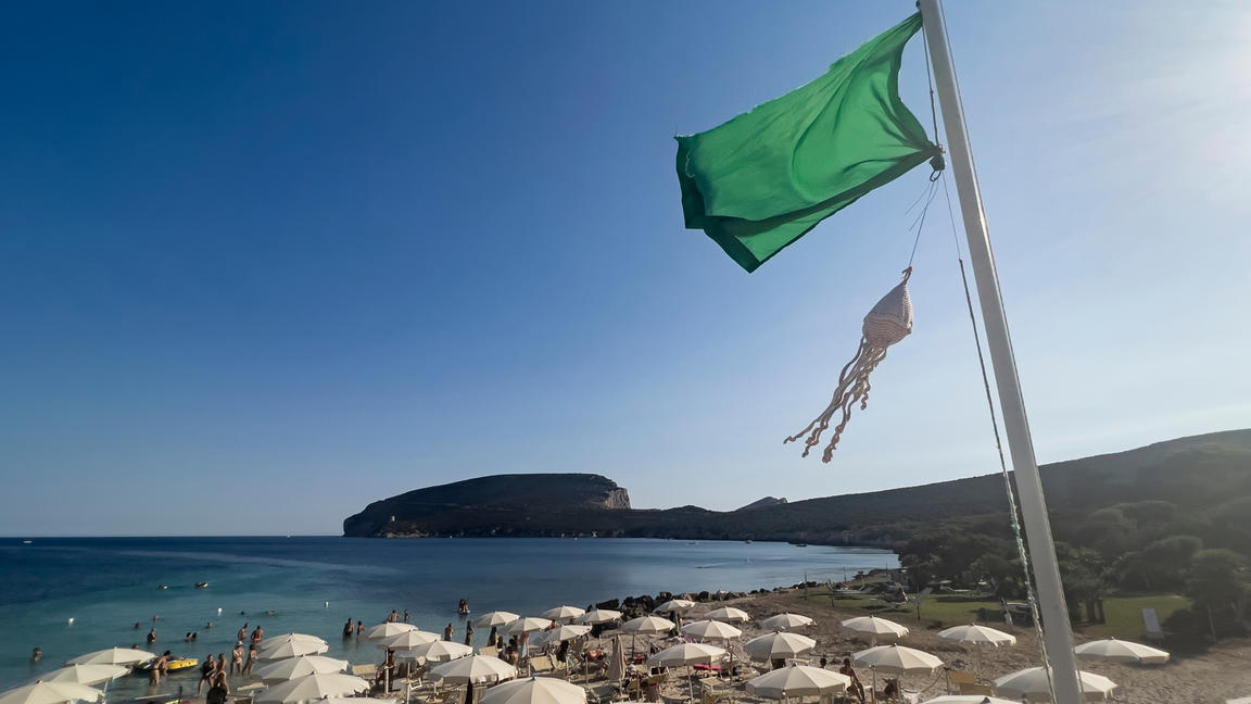 Fahne weht  an einem Strand bei Alghero auf Sardinien, Italien.