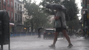 25.07.2022, USA, New York: Ein Mann mit Regenschirm geht bei heftigen Gewitterschauern im Stadtteil Williamsburg in Brooklyn über eine Straße. Foto: Edna Leshowitz/ZUMA Press Wire/dpa +++ dpa-Bildfunk +++